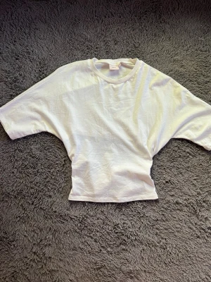 Vit croppad topp med knyt i ryggen - Säljer en vit croppad topp med korta ärmar och rund halsringning. Toppen har en öppen rygg med knytband som ger en snygg detalj. Perfekt till jeans eller kjol för en trendig look. Tröjan är från Nelly och nypris är 259 kr, jag tycker att den är så snygg men jag har en till hemma så därför säljer jag denna!☺️