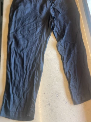 Svarta linnebyxor från Ellos - Snygga svarta linnebyxor från Ellos med avslappnad passform och resår i midjan. Perfekta för en chill och stilren look. Tillverkade i lätt och luftigt linnematerial som passar perfekt till varmare dagar.