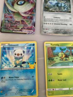 Fyra Pokémonkort blandade motiv - Samling med fyra Pokémonkort med olika motiv, inklusive Oshawott och Turtwig. Korten har färgstarka illustrationer och text på både engelska och tyska. Perfekt för dig som gillar att samla eller spela Pokémon TCG.