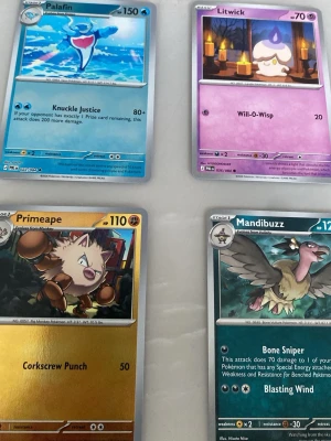Fyra Pokémonkort i olika färger - Säljer fyra Pokémonkort: Palafin (blå), Litwick (lila), Primeape (gul) och Mandibuzz (grön). Korten har olika illustrationer och attacker, och är tillverkade i klassiskt Pokémonkort-material. Perfekt för samlare eller dig som vill spela Pokémon TCG.