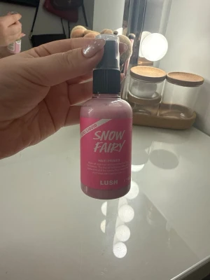 Lush Snow Fairy Hair Primer - Lush Snow Fairy Hair Primer är en hårprimer i en rosa plastflaska med spraymunstycke. Produkten har en söt och lekfull design med vit text och är perfekt för att förbereda håret inför styling. Flaskan är smidig att använda och enkel att ta med sig. Sprayat 1 gång 