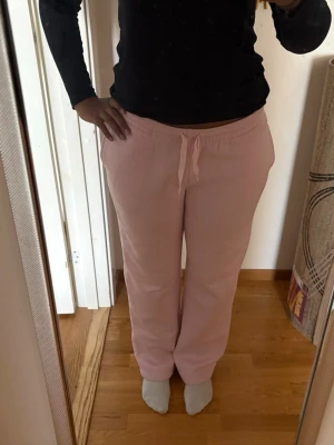 Ljusrosa mjuka loungebyxor - Superbekväma ljusrosa loungebyxor med resår och dragsko i midjan. Byxorna har raka ben och är perfekta för att chilla hemma. Tillverkade i ett mjukt och skönt material som känns härligt mot huden.