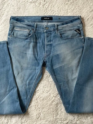 Ljusblå jeans från Replay - Snygga ljusblå jeans från Replay med klassisk femficksdesign och diskreta slitningar framtill. Jeansen har raka ben och detaljerade bakfickor med sömmar. Perfekta för en avslappnad och trendig look.