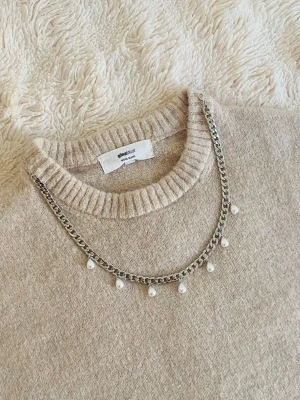 Silverfärgat halsband med pärlor - Stilrent halsband i silverfärgad rostfritt med kedja och hängande vita pärlor. Kedjan har en chunky känsla och pärlorna ger en elegant touch. Perfekt för att lyfta vilken outfit som helst med en trendig och modern vibe.