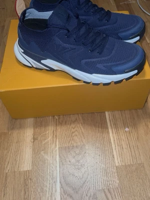 Lv skor - Snygga mörkblå sneakers med stickad ovandel och robust vit sula med svarta detaljer. Skorna har lågt skaft och sportig design, perfekta för en trendig streetstyle-look. Materialet är mesh och syntet för bra komfort och andningsförmåga.