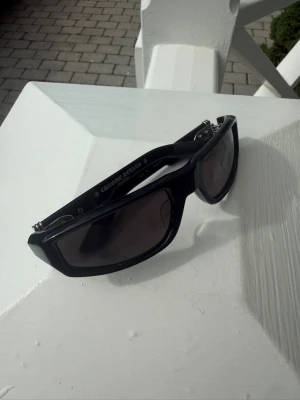 Chrome Hearts HT - Säljer ett par chunky svarta solglasögon från Chrome Hearts med bred båge och mörka glas. Snygga silverdetaljer vid gångjärnen ger en exklusiv känsla. 