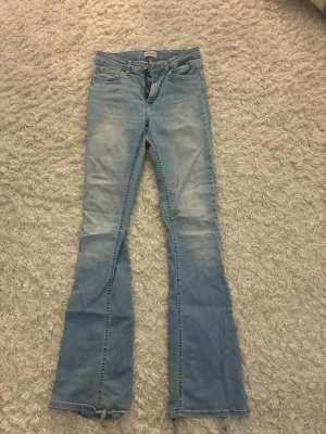 Ljusblå bootcut jeans - Säljer ett par ljusblå bootcut jeans från Only. Väl använda, lite trasiga längst ner pga att de är rätt så långa och även en lite limfläck på låret men inget som märks.