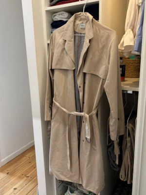 Beige trenchcoat från ONLY - Stilren beige trenchcoat från ONLY med knytband i midjan. Perfekt för vår och höst. Sparsamt använd. 🤗🤗