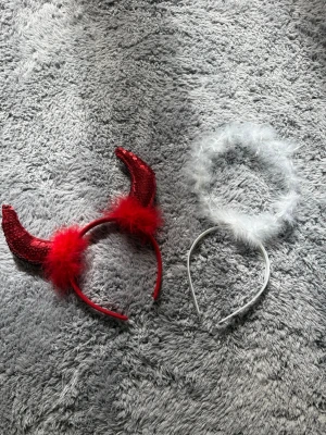 Djävulshorn och ängladiadem - Säljer ett set med ett rött diadem med glittriga paljett-horn och fluffiga fjädrar samt ett vitt diadem med mjuk fjädergloria. Perfekt till maskerad eller cosplay. Materialet är plast, tyg och fjädrar.