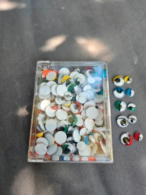 Färgglada rörliga plastögon - En ask med blandade rörliga plastögon i olika färger som grönt, gult, blått och rött. Perfekta till maskerad eller pyssel. Ögonen har svarta fransar och kommer i olika storlekar. Lätta att limma fast på masker eller dräkter.