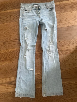 Ljusblå slitna bootcut jeans - Säljer dessa jätte snygga bootcut jeansen! Det är ett par dolce Gabbana jeans med slitningar. 