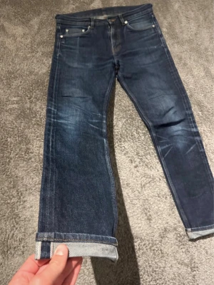 Mörkblå raka jeans med uppvik - Snygga  mörkblå selvadge jeans med raka ben. Jeansen har klassisk femficksdesign. A:38 B:70 C:23 D:19 E:15 Jeansen har blivit skurna i midjan för att passa bättre.