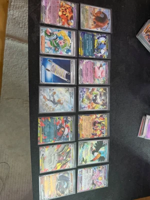 Pokémonkort samling i plastfickor - En samling Pokémonkort med färgstarka motiv och holografiska effekter. Korten visar olika Pokémon och tränare, och alla ligger i genomskinliga plastfickor. Materialet är papp och plast, och motiven är detaljerade och varierade. Perfekt för samlare eller Pokémonfans.