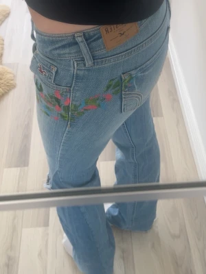 Snygga Hollister jeans🌸🩵 - Jätte snygga men tyvärr lite tighta på mig😵 har lite blommor på sig som design🌸 strl 27 men mindre i storlek 🥰 skriv för mer frågor och bilder🙏🏻