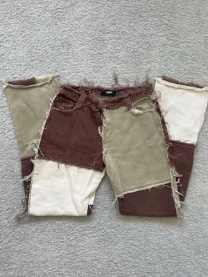 Patchwork jeans från Jaded London - Unika patchwork jeans från Jaded London i beige, brunt och offwhite i storlek W25. Modellen har råa kanter och fransiga detaljer för en edgy look. Tillverkade i kraftigt bomullstyg med raka ben och hög midja. Köptes ett tag sedan för ca 800kr🥰