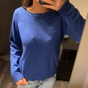 Blå stickad tröja från VILA - Snygg blå stickad tröja från VILA i storlek M. Tröjan har rund halsringning, ribbade muddar vid ärmslut och nederkant samt långärmad passform. Perfekt att matcha med jeans för en chill look. Materialet känns mjukt och skönt mot huden.