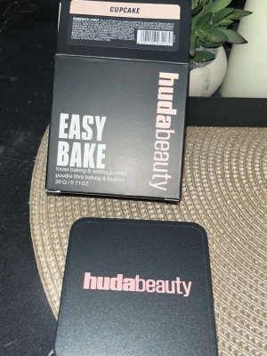 Huda Beauty Easy Bake Cupcake puder - Huda Beauty Easy Bake Loose Baking & Setting Powder i nyansen Cupcake. Kommer i en svart fyrkantig burk med rosa text och matchande kartong. Löst puder som ger en matt finish och fixerar makeupen. Innehåller 20 g.