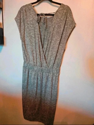 Klänning Lindex M - En enkel och stilren gråmelerad klänning med resår i midjan och korta ärmar. Klänningen har rund halsringning och är tillverkad i mjukt bomullsmaterial. Perfekt för en avslappnad look.