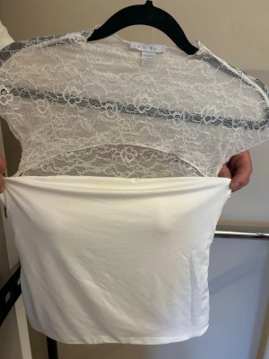 Vit spetsblus från Amisu - Säljer en superfin vit blus från Amisu med transparent spets upptill och slät, mjuk nederdel. Aldrig använd