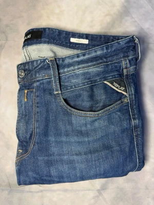 Blå jeans från Replay - Snygga blå jeans från Replay med klassisk femficksmodell och ljus tvätt. Jeansen har raka ben och detaljerade sömmar i kontrastfärg. Materialet är mjukt denim som ger en avslappnad look. Perfekta för dig som gillar stilrena och tidlösa jeans. Storlek 34/32