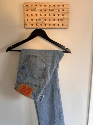 Levi's ljusblå raka jeans - Klassiska ljusblå jeans från Levi's med rak passform och femficksmodell. Jeansen har en ikonisk läderpatch bak och röd Levi's-tagg på bakfickan. Perfekta för en avslappnad och tidlös stil.