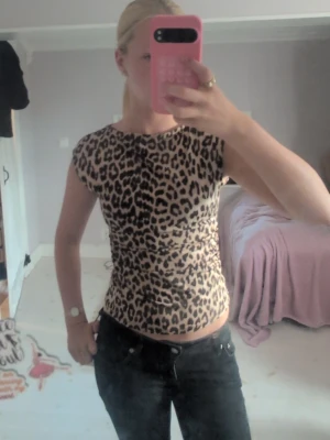 Leopardmönstrad tight topp - Säljer en leopardmönstrad topp med korta ärmar och rund hals. Toppen är tight i passformen och har ett mjukt, stretchigt material som sitter snyggt på kroppen. Perfekt för dig som vill sticka ut lite extra med ett djurmönster.