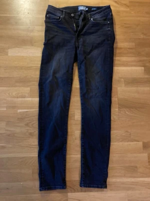 Svarta slim fit jeans med snygg tvätt - Säljer ett par svagta slim fit jeans med klassisk femficksdesign och normalhög midja. Jeansen har smala ben och är tillverkade i ett stretchigt denimtyg för extra komfort. Perfekta för en avslappnad och trendig look.