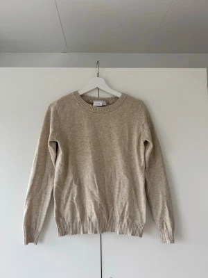 Beige stickad tröja från Vila - Säljer en fin beige stickad tröja från Vila, i storlek XS. Tröjan har en åtsittande passform.  Den är använd ett fåtal gånger och har inga större tecken på användning💕