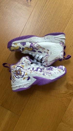 Basket skor vita och lila  - Snygga basket/idrotts skor. De har en lila sula och vitt och lila mönster. De har numret 23 på sidan av skon. Jag tar emot byten.