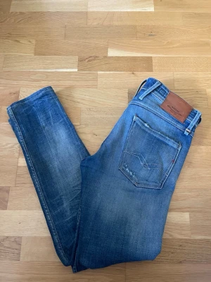 Replay anbass - Säljer ett par blå jeans från Replay med model anbass och slitningar. Perfekta för en avslappnad och trendig look. Hör av er vid funderingar!