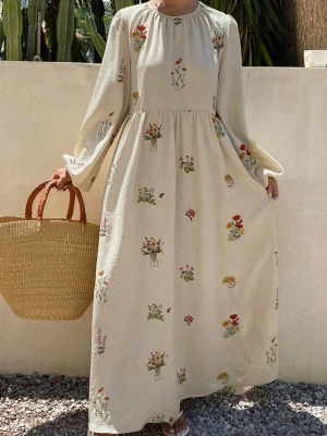 Ljusbeige maxiklänning med blommor - Lång, ljusbeige maxiklänning med löst sittande passform och ballongärmar. Klänningen har broderade blommor i olika färger över hela tyget och rund halsringning. Perfekt för en bohemisk och avslappnad stil.