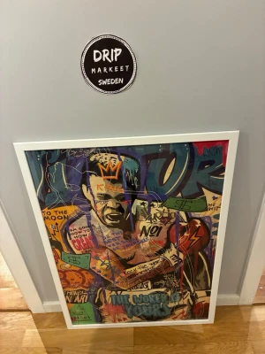  tavla 50 x 70  - Säljer en tavla i 50 x 70 formatet med popkonst och graffiti-inspirerat av mohammed ali köpt på konstmuseum i amsterdam den har motiv i starka färger som blått, orange, rött och grönt. Tavlan har vit ram och motivet innehåller text, symboler och en uttrycksfull person. Perfekt för dig som gillar modern konst och vill ha något unikt på väggen.