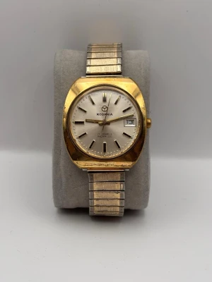 Rodania vintage klocka i guld och silver - Snygg vintageklocka från Rodania med rund urtavla i vitt, guldfärgad boett och silverfärgad länk. Klockan har datumvisning och klassisk design som passar perfekt till din stil. Metallarmbandet ger en tidlös känsla.