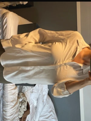 Vit  långärmad skjorta - Säljer en stilren vit skjorta med klassisk krage och knappar framtill. Skjortan är långärmad och har en avslappnad passform, perfekt för en clean och enkel look. Liten sminkfläck, går troligtvis bort i tvätt