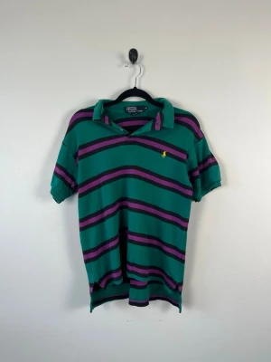 Vintage Polo Ralph Lauren Piké M Grön Lila Randig 90s Y2K USA 100% Bomull Herr - • Storlek: M • Färg: Mörkgrön • Passform: Classic Fit  • Krage: Klassisk pikékrage • Material: 100% bomull  Skick: Plagget är i väldigt fint skick med ett litet hål som syns på bild. Eventuella anmärkningar anges alltid tydligt i beskrivningen och visas på bilderna.  Nypris: Cirka 1 400 kr.  📦 Skickas snabbt och packas omsorgsfullt. 💬 Hör gärna av dig om du har frågor eller vill se fler bilder. 🤝 Samfrakt erbjuds vid köp av flera plagg – kika gärna in mina andra annonser!