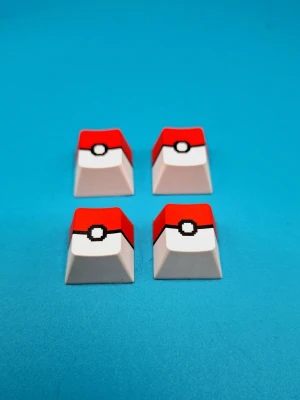 Keycaps-set - Säljer fyra keycaps till tangentbord med Pokeball-design i rött, vitt och svart. Tillverkade i plast och passar tangentbort med.plus-fäste. Perfekt för dig som vill ge tangentbordet en unik och nördig touch.