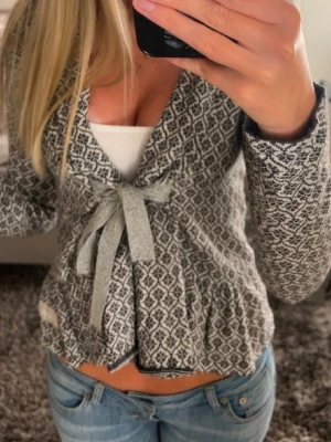 Odd Molly kofta - Supersöt grå och vit kofta med stickat mönster och knytband framtill. Koftan har en omlott-look och långa ärmar, perfekt för lager på lager. Passar till jeans eller kjol för en chill men ändå stylish vibe. Den är från Odd Molly i jättefint skick! Storleken skulle jag säga är S