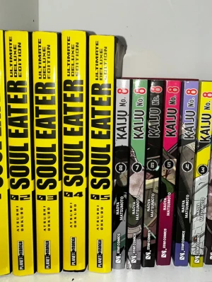 Soul Eater och Kaiju No. 8 manga Italienska - Samling med flera volymer av Soul Eater Ultimate Deluxe Edition med gul rygg och svart text samt Kaiju No. 8 i olika färger. Perfekt för dig som gillar manga och actionfyllda berättelser. Böckerna har tydliga omslag och är på Italienska.