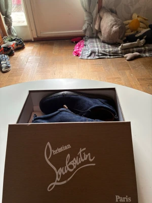 Mörkblå sneakers från Christian Louboutin - Snygga mörkblå sneakers från Christian Louboutin i mocka med klassisk röd sula. Skorna har en låg profil och stilrena snörningar. Perfekta för dig som vill ha något exklusivt och trendigt i garderoben.