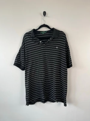 Vintage Lauren Ralph Lauren Piké M Svart Vit Randig Dam 100% Bomull Polo Retro - • Storlek: M • Färg: Svart med vita/tunna ljusa ränder • Passform: Relaxed Fit  • Krage: Klassisk pikékrage • Material: 100% bomull  Skick: Plagget är i väldigt fint skick. Eventuella anmärkningar anges alltid tydligt i beskrivningen och visas på bilderna.  Nypris: Cirka 1 400 kr.  📦 Skickas snabbt och packas omsorgsfullt. 💬 Hör gärna av dig om du har frågor eller vill se fler bilder. 🤝 Samfrakt erbjuds vid köp av flera plagg – kika gärna in mina andra annonser!• Storlek: M • Färg: Svart med vit