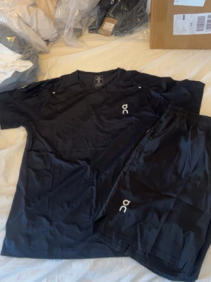 Set med t-shirt och shorts från On - Säljer två sportiga set från On, ett i svart och ett i ljusgrönt. Båda seten består av en t-shirt och matchande shorts i lätt och snabbtorkande material. Perfekta för träning eller löpning, med minimalistisk design och On-logga på både tröja och shorts.