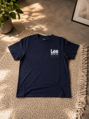 Marinblå Lee t-shirt med tryck - Snygg marinblå t-shirt från Lee med coolt tryck på bröstet där det står 'Lee Jeans 1889'. Klassisk passform och rund halsringning. Perfekt till jeans eller shorts för en avslappnad look. Det finns tecken på användning (se bilder)