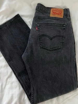 Svarta Levi's superlow boot - Säljer ett par mörk gråa bootcut Levi's och klassisk femficksdesign. Jeansen har en vintage tvätt och är tillverkade i slitstark denim. 