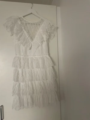 Vit spetsklänning med volanger - Supersöt vit kortklänning i spets. Den är helt slutsåld på zalando i xs helt oanvänd!!(nypris 969kr) passar perfekt till studenten/konfirmation