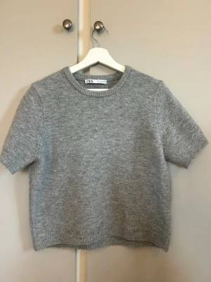 Grå stickad t-shirt från ZARA - Stickad t-shirt från Zara, Säljer pga att tröjan är för stor för mig. Om du söker en mer oversized tröja rekommenderar jag att du går upp 1 eller 2 storlekar💞 OBS! Använd fåtal gånger