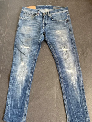 Dondup george jeans - 0 Defekter, nästan ny,Säljer ett par blå Dondup jeans med slitningar och distressed detaljer på benen. Jeansen har klassisk femficksmodell, normal midja och raka ben. Perfekta för en avslappnad och trendig look. Slim fit