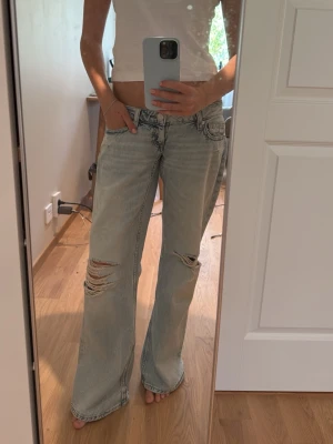 Low waist vida jeans med slitningar från Gina tricot 14 + - Jeansen är i storlek s. De är i perfekt skick då jag köpte de nya från vinted oanvända. De är i en fin ljusblå färg som passar till de flesta topparna och tröjorna!