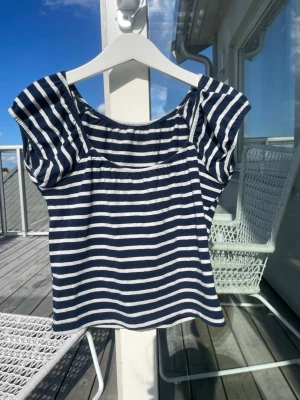 Randig topp med puffärm - Säljer en marinblå och vit randig topp med puffiga korta ärmar och rundad halsringning från brandy Melville!