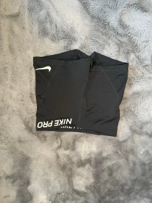 Svarta Nike Pro shorts Dri-FIT - Säljer ett par svarta Nike Pro shorts med Dri-FIT-teknologi. De har en tight passform, elastisk midja och vit Nike-logga samt texten NIKE PRO på benet. Perfekta för träning och sportaktiviteter.