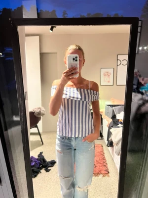 Randig offshoulder topp blå/vit - Säljer en snygg offshoulder topp med blå och vita vertikala ränder. Toppen har smala axelband och en croppad passform som ger en fräsch sommarkänsla. Perfekt till ett par jeans eller kjol för en trendig look. Skriv för frågor🩷🫶🏼